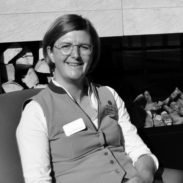 Schwarzweiß-Portrait: Frau mit Brille, Weste und Ausweisband, lachend
