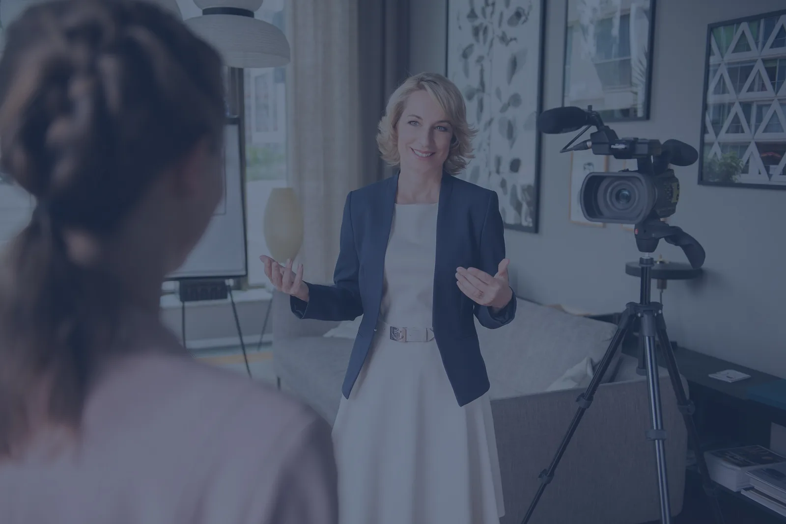 Frau in blauem Blazer bei Videoaufnahme im Studio mit Kamera auf Stativ