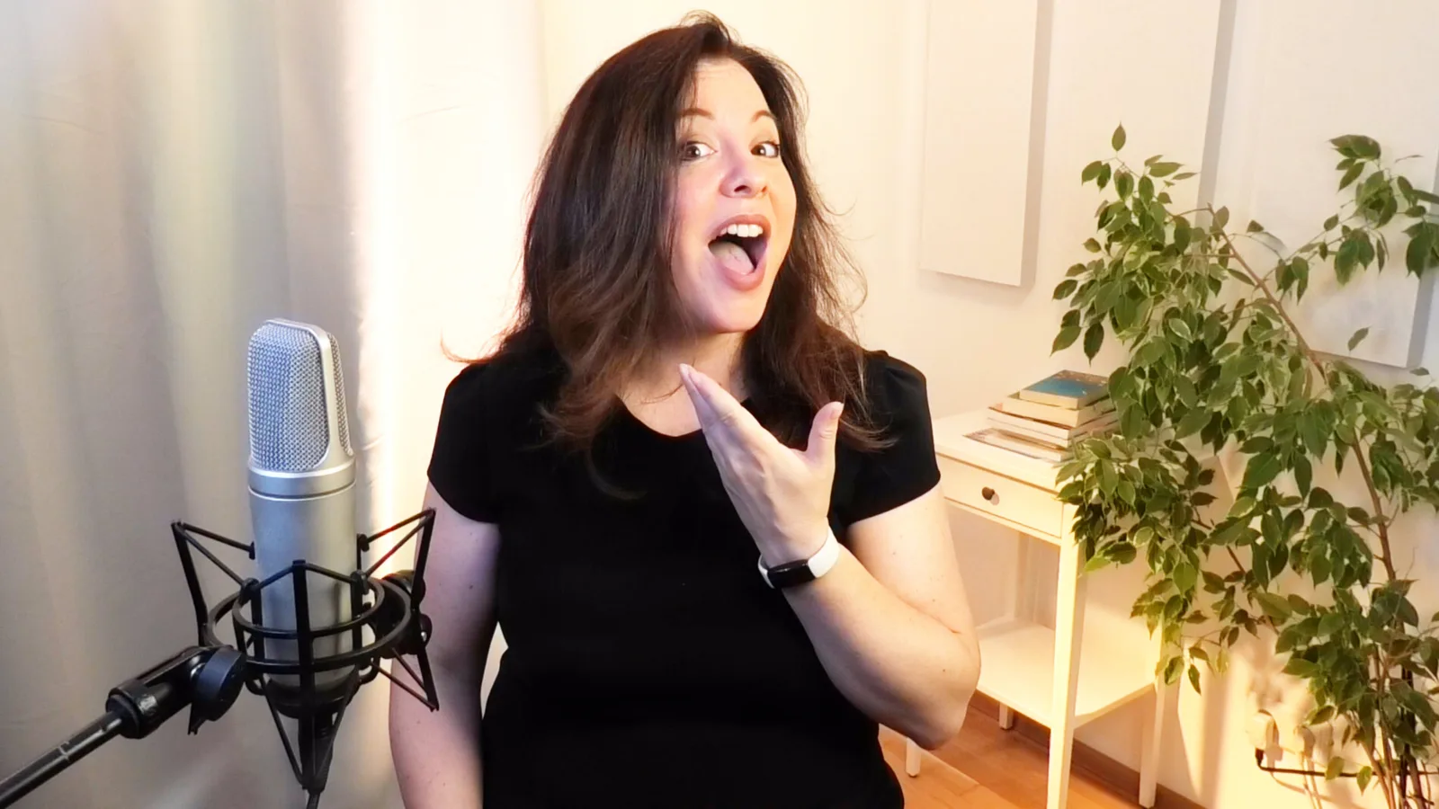 Frau spricht begeistert am Mikrofon, Studio-Setup mit Pflanze