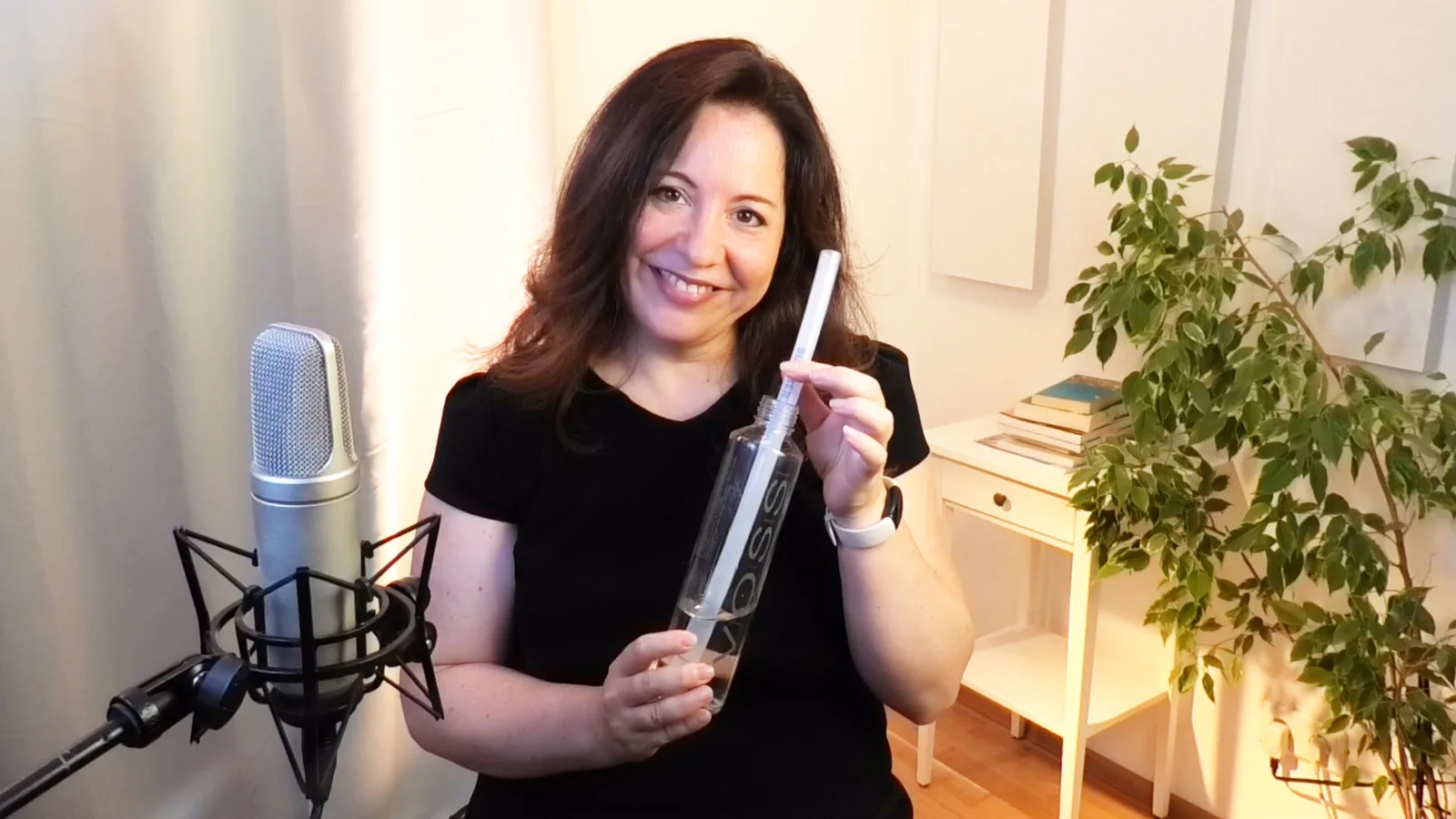 Frau zeigt Sprachtraining-Produkt am Mikrofon, Studio-Umgebung