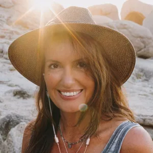 Portrait Sandra Weber – Frau mit Strohhut und Sonnenbrille am Strand
