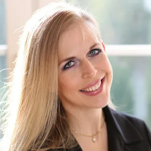 Porträt von Sonja Volk, Frau mit blondem Haar im schwarzen Jacket