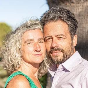 Porträtfoto eines Paares (Frau und Mann) vor unscharfem Hintergrund, beide lächelnd