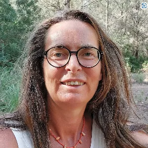 Porträtfoto von Heike Rieck mit Brille und braunem Haar vor grünem Naturhintergrund