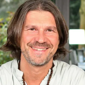 Porträt von Ralph Riedel, Mann mit langen Haaren und Bart lächelnd