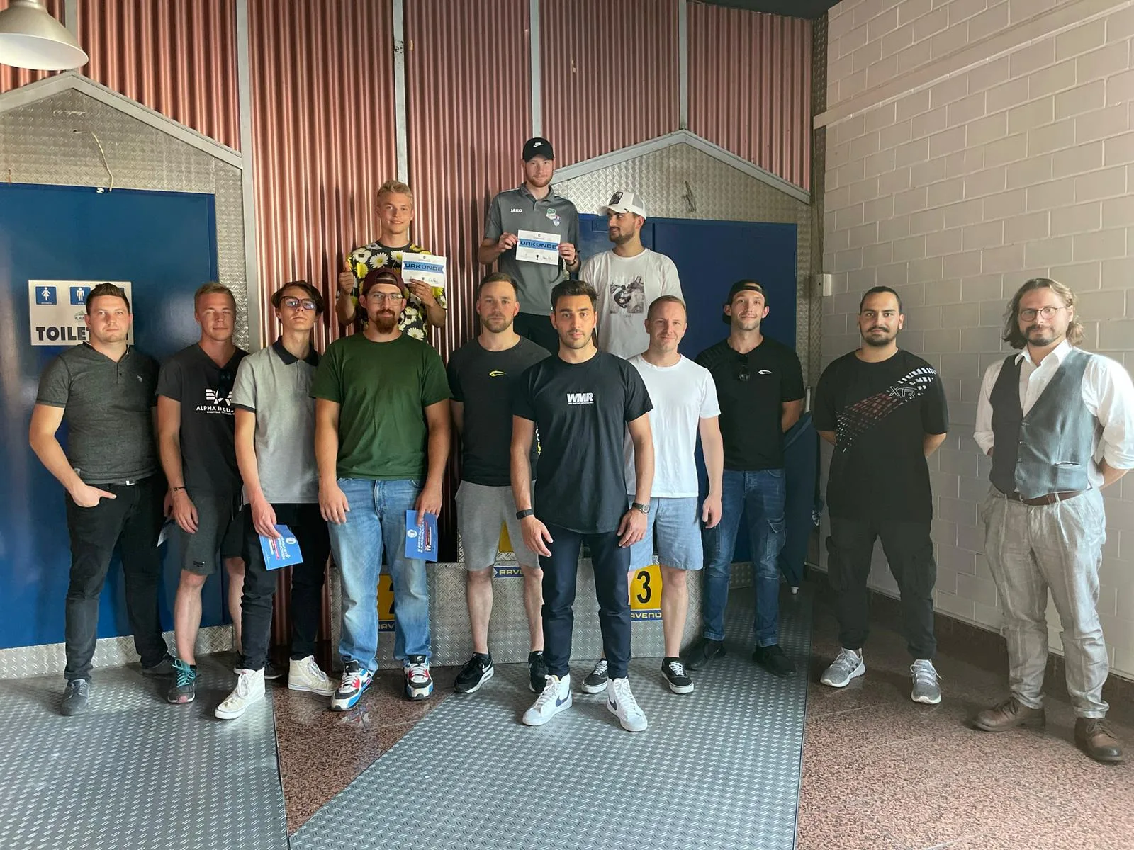 Gruppenfoto von elf Trainingsteilnehmern mit zwei Gewinnern auf Podium