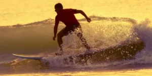 Surfer bei Sonnenuntergang auf einer Welle, Take Off Intensiv Training