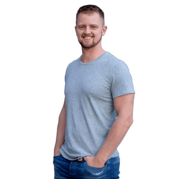Junger Mann in grauem T-Shirt und Jeans lächelt in die Kamera
