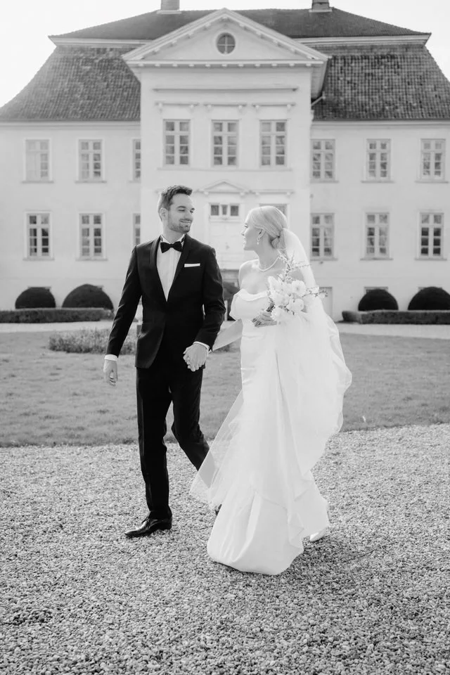 Schwarzweiß-Hochzeitsfoto eines Brautpaares vor Schloss Gut Hasselburg