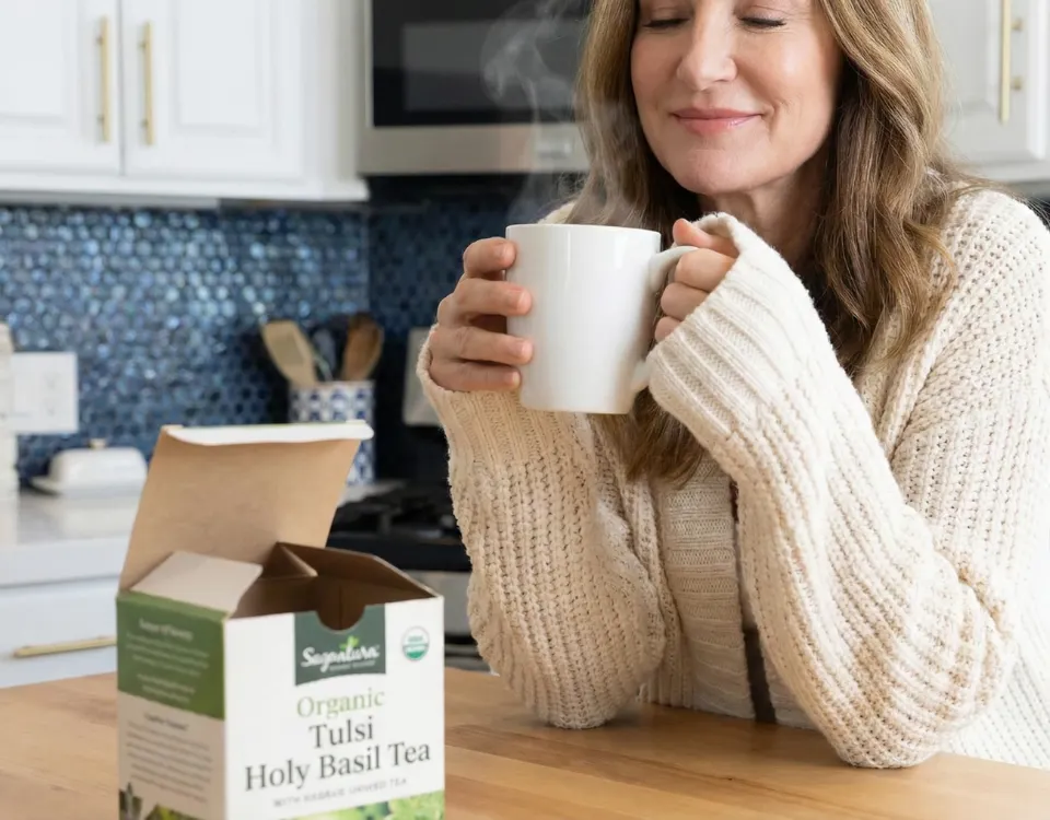 The Herbal Remedy Companion – E-Book über Kräuter-Hausmittel 10 Frau trinkt Tulsi Holy Basil Tee aus weißer Tasse in der Küche