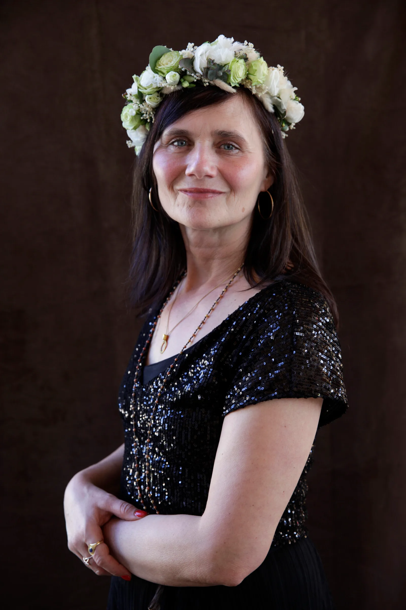 Porträt von Frau mit Blumenkranz auf dunklem Hintergrund, nachdenklicher Blick