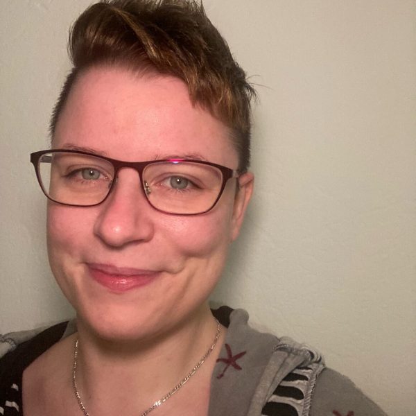 Porträt einer Person mit Brille und braunen Haaren, lächelnd