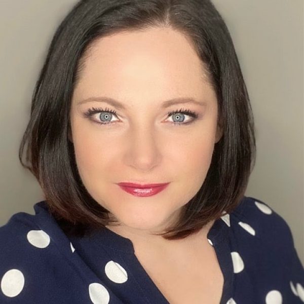 Porträt einer Frau mit dunklen Haaren und fuchsia-farbenem Lippenstift in dunklem Oberteil