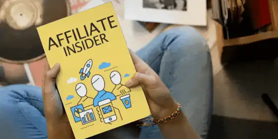 TikTok Marketing Insider-Hacks – Videokurs für Affiliate-Umsatz 4 Hände halten gelbes Buch mit Titel Affiliate Insider und Grafiken vor unscharfem Hintergrund