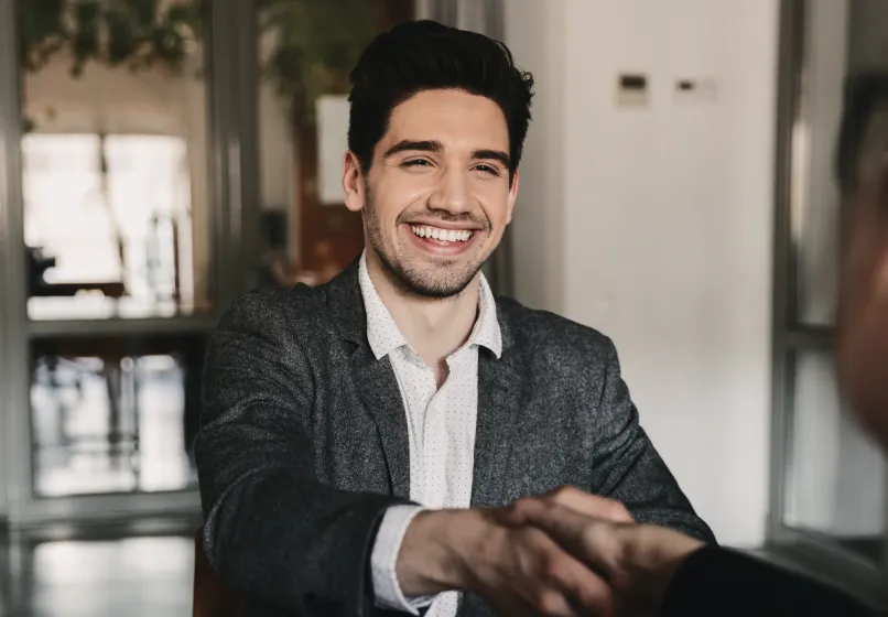 Porträt eines lächelnden jungen Mannes im dunklen Blazer und weißem Hemd