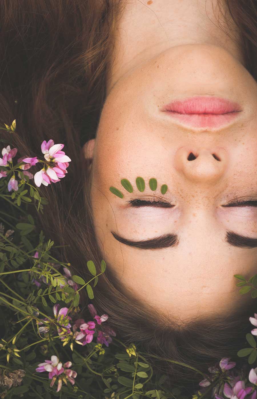 Gesicht einer Frau mit Blumen und grünem Augen-Make-up