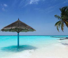 Tropischer Strand mit Strohdach-Sonnenschirm, türkisem Wasser und Palmen