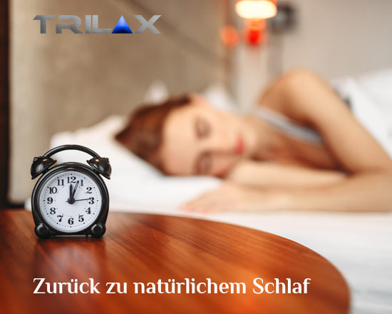 Schlafende Person im Bett mit Wecker auf Holztisch und Trilax Logo