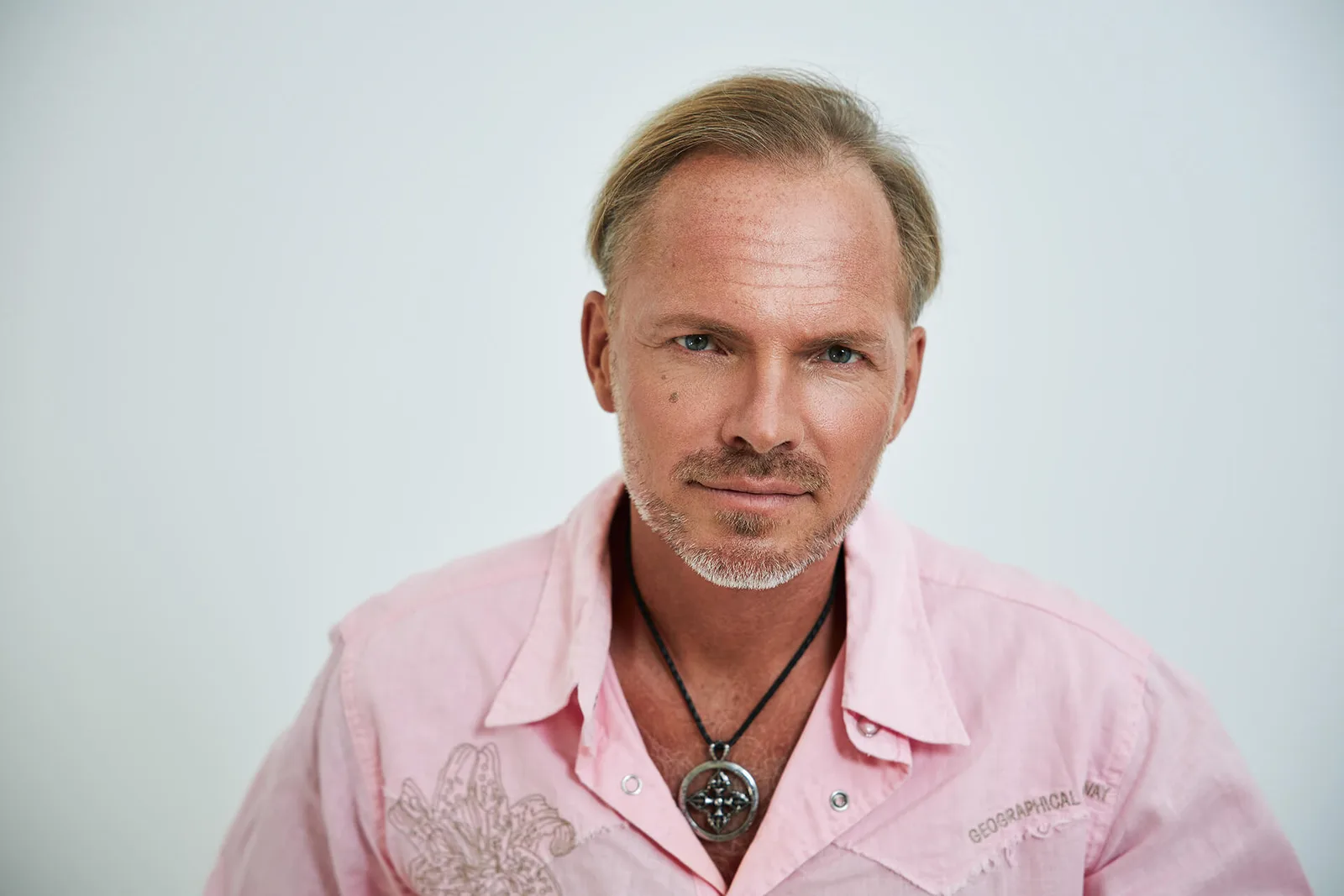 TUN – Videokurs gegen Aufschieben von Siranus Sven von Staden 5 Portrait von Siranus Sven von Staden in rosa Hemd mit Kettenanhänger vor weißem Hintergrund