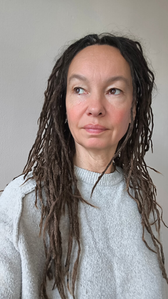 Porträt von Ludmilla Rudat mit langen dunklen Dreadlocks und grauem Pullover