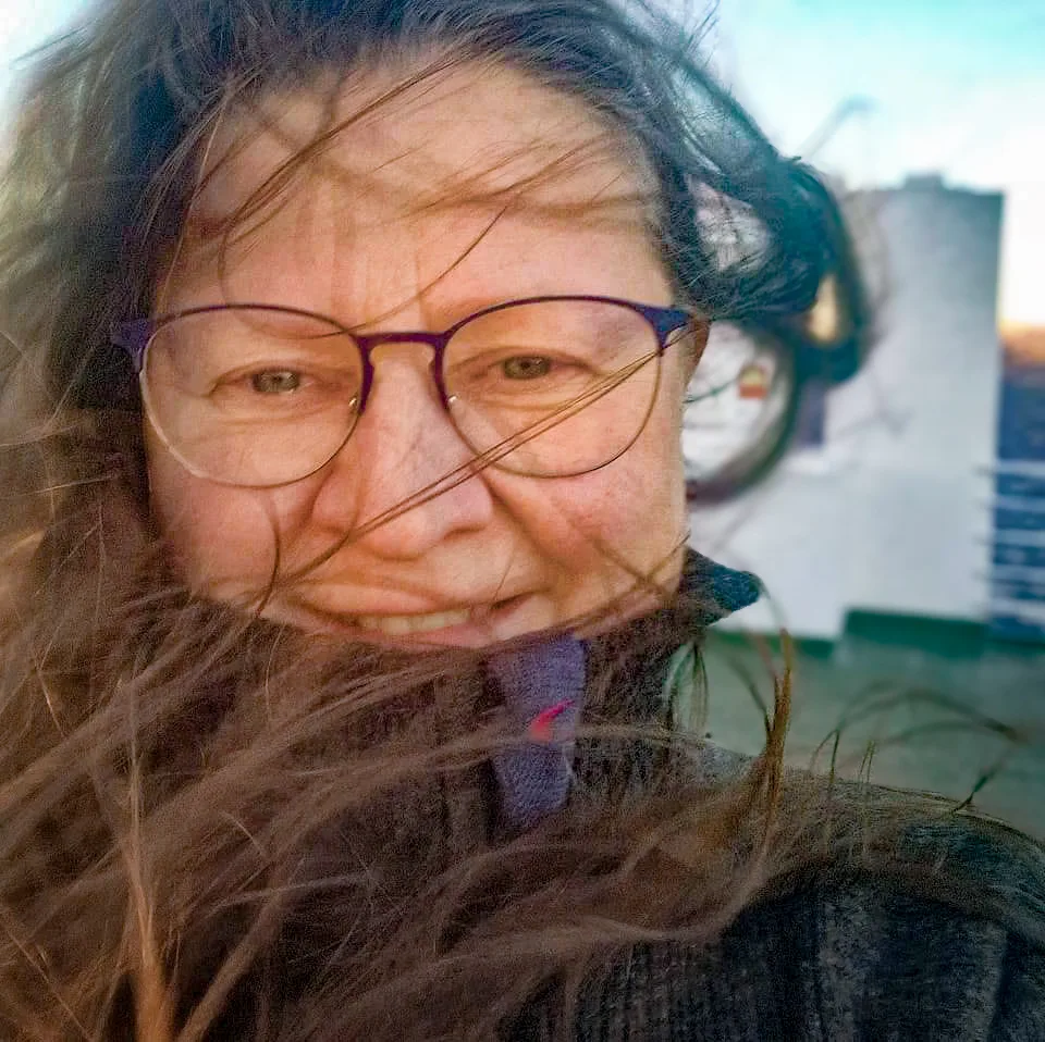 Frau mit Brille und langen Haaren bei windigem Wetter im Freien