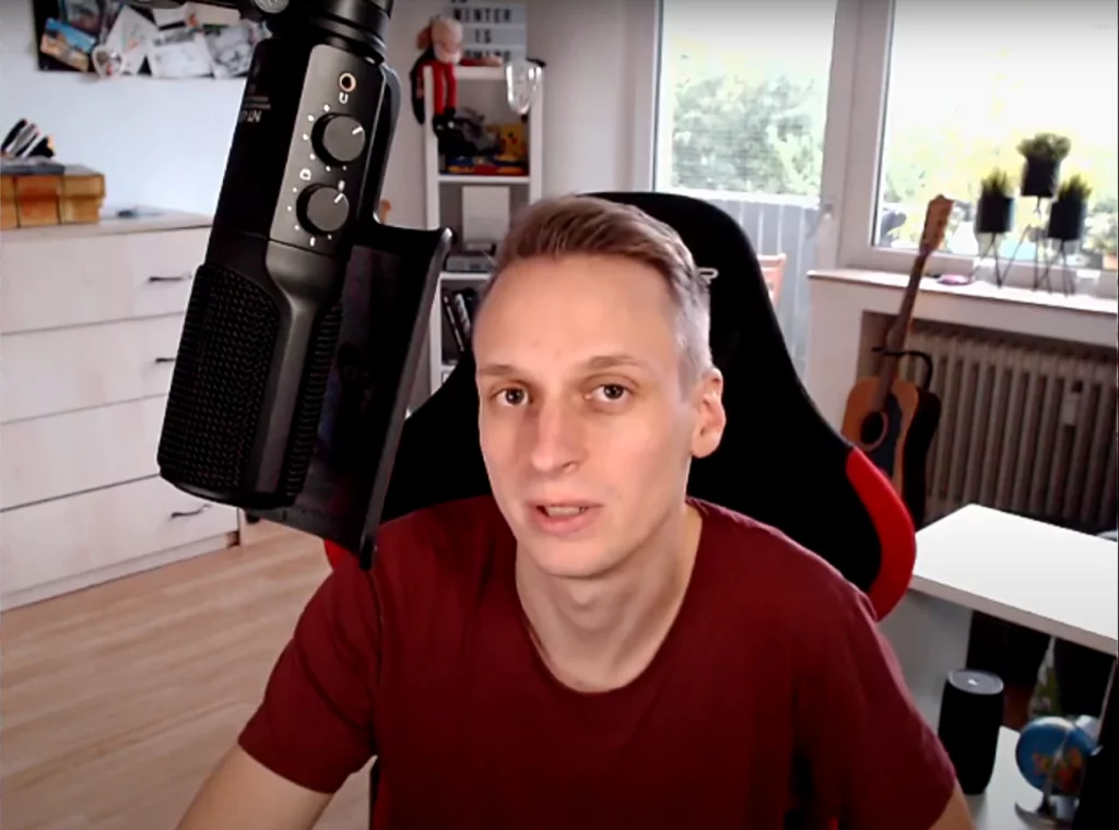 Junger Mann spricht vor Mikrofon im Büro während einer Video-Anleitung