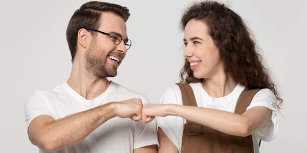 Mann und Frau machen fröhlich Fist Bump, beide lächeln sich an