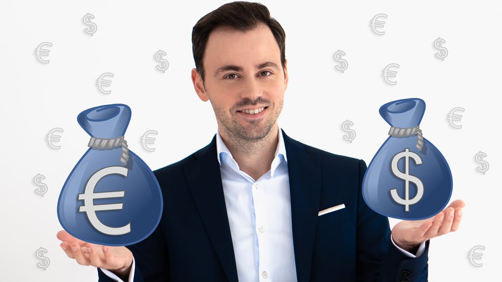 Lächelnder Mann in dunklem Anzug hält zwei blaue Geldsäcke mit Dollar und Euro Symbolen