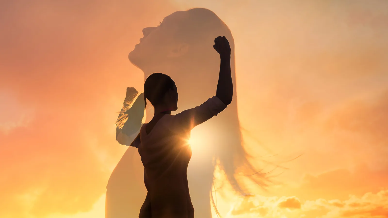 Frau mit erhobener Faust im Gegenlicht vor goldenem Sonnenuntergang und Wolkenformation