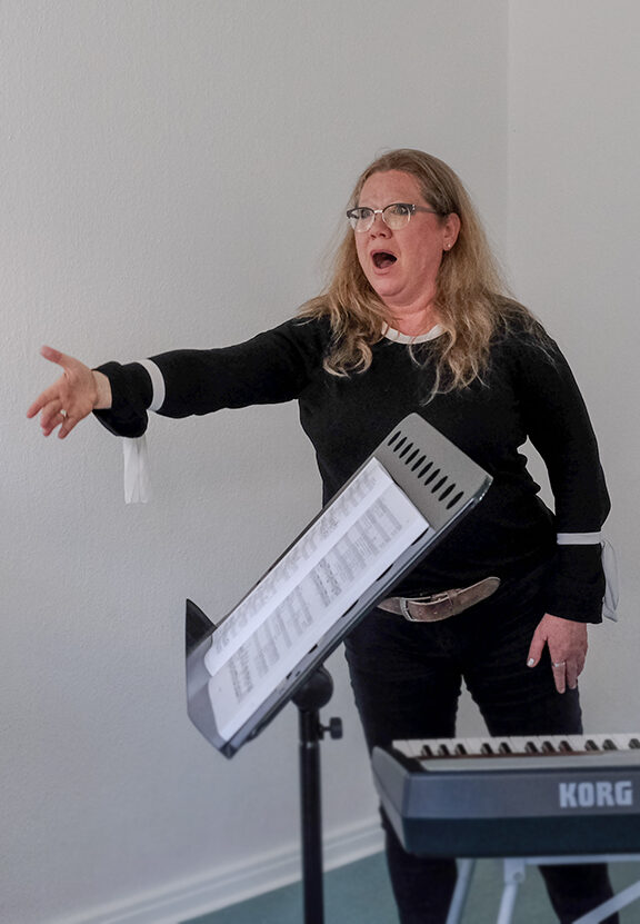 Tanja Rossis singend mit Keyboard, Frau mit Brille und langen Haaren in schwarzem Pullover