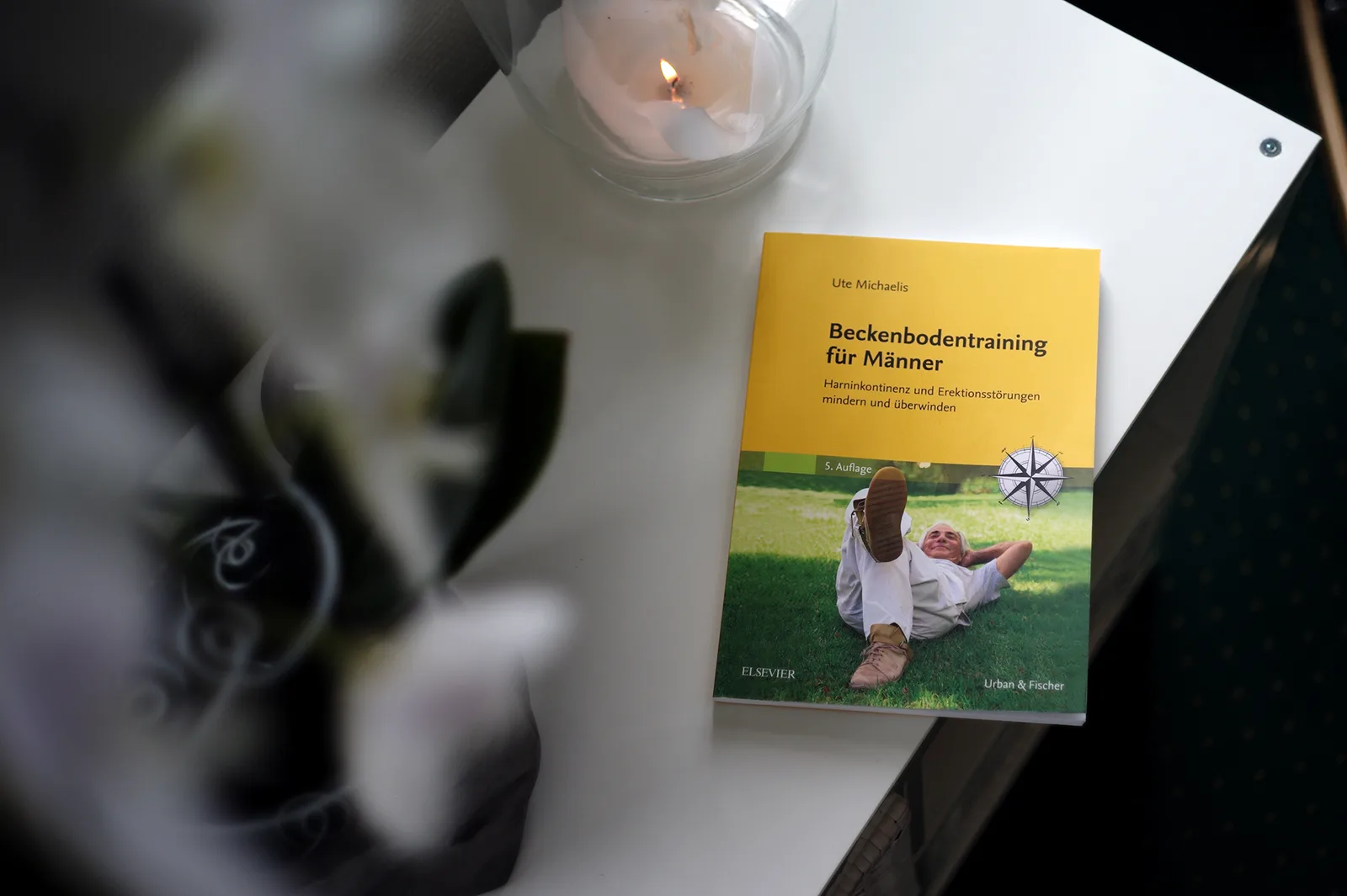 Vorbereitungskurs Prostata-OP – Videokurs für Kontinenz-Training 8 Sachbuch Beckenbodentraining für Männer von Ute Michaelis, 5. Auflage, auf weißem Tisch mit Kerze