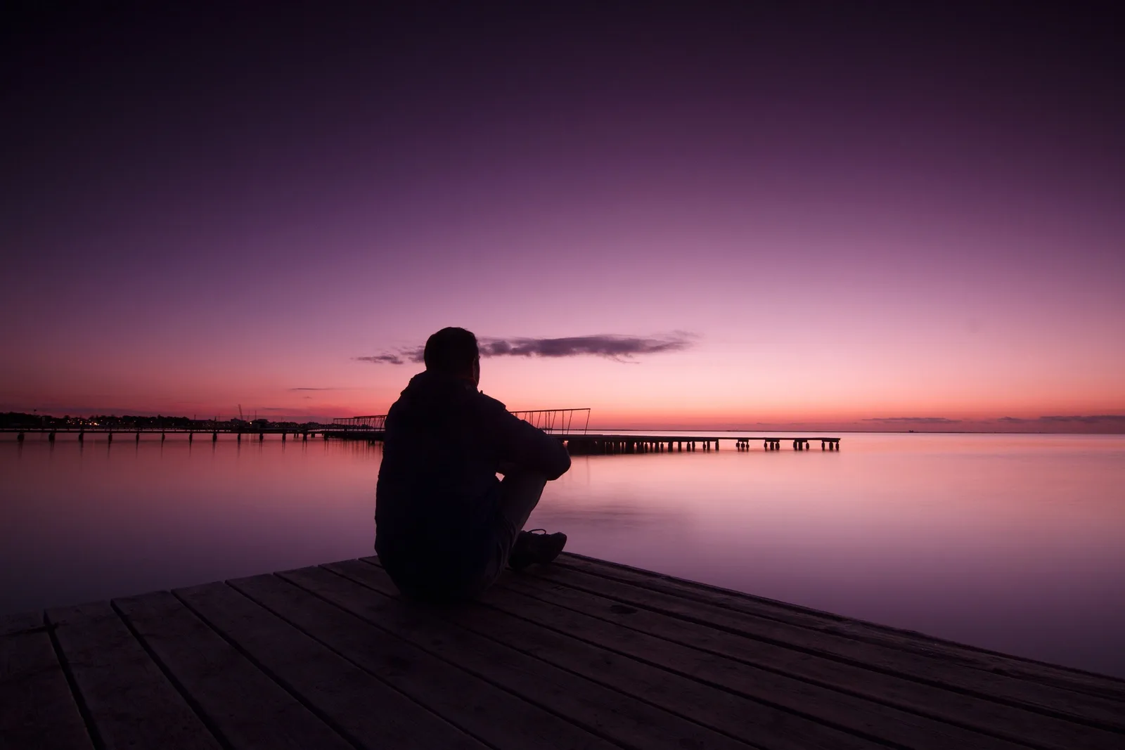 Was Dich Nährt 25 – Kongresspaket zu Gesundheit von Iris Zimmer 6 Silhouette eines Mannes bei Sonnenuntergang auf Holzsteg am ruhigen Wasser mit Bootssteg im Hintergrund