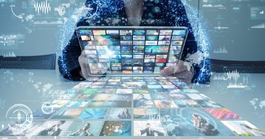 Person hält Laptop mit Vimeo-Videostreams und glühenden Dateneffekten