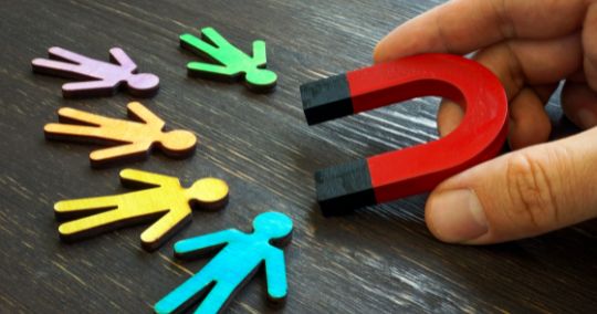 Rote Hufeisen-Magnet zieht bunte menschliche Figuren aus Papier an