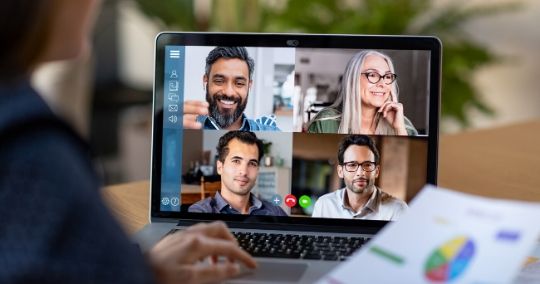 Laptop-Bildschirm zeigt Videokonferenz mit vier Teilnehmern in verschiedenen Fenstern