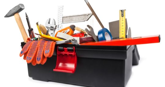 Schwarzer Werkzeugkasten gefüllt mit verschiedensten Werkzeugen und Handschuhen
