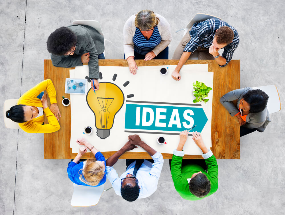 Webinar-Bundle – Videokurse zur Bewerbung von Tanja Herrmann-Hurtzig 9 Draufsicht auf Gruppe von sieben Personen um Holztisch mit IDEAS-Banner