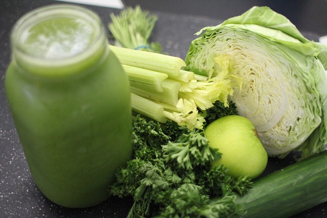 Grüner Saft in Glas mit frischem Gemüse wie Salat, Sellerie, Kale und Apfel