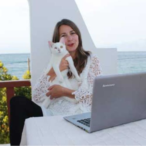 Anna Roth mit weißer Katze am Laptop, Meerblick im Hintergrund