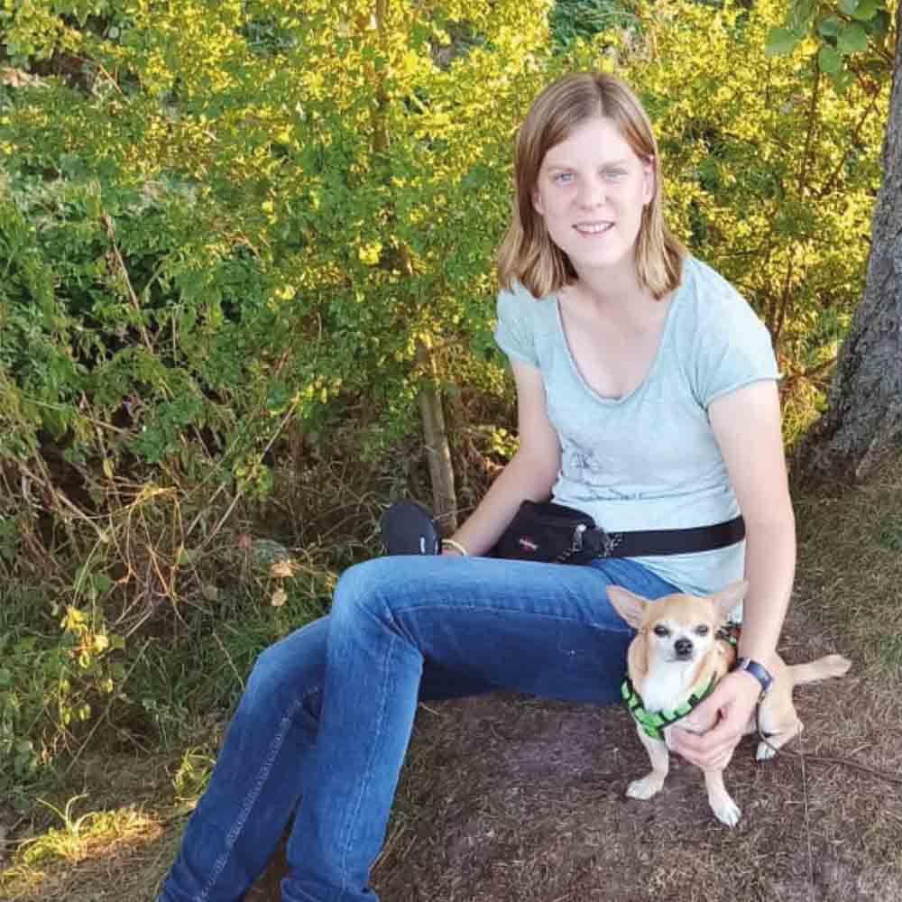 Lisa Zimmer mit tan-farbenem Chihuahua vor gelbem Buschwerk