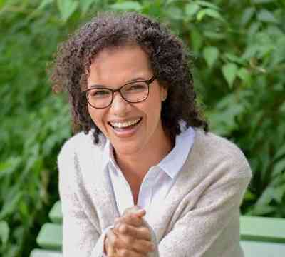 Wie geht Selbstliebe? – Videokongress zur Selbstliebe 35 Porträt von Jessica Samuel, Frau mit braunem lockigem Haar und Brille vor grünem Hintergrund