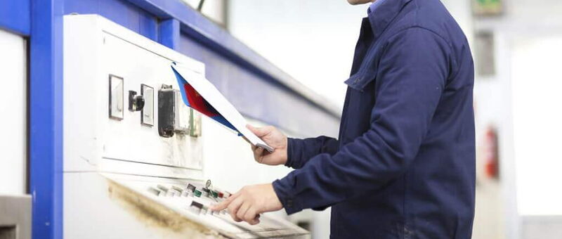 Elektrofachkraft mit Prüfgerät an Elektroanlage mit blauen Rahmen