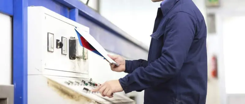 Elektrofachkraft mit Prüfgerät an Elektroanlage mit blauen Rahmen