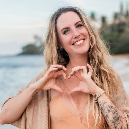 Lia Lohmann Porträt, blonde lange Haare, lächelnd, Strand mit Wasser im Hintergrund