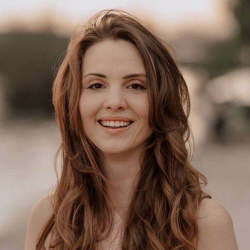 Clara Fink Porträt, blonde mittellange Haare, Blumenschmuck, lächelnd, heller Hintergrund