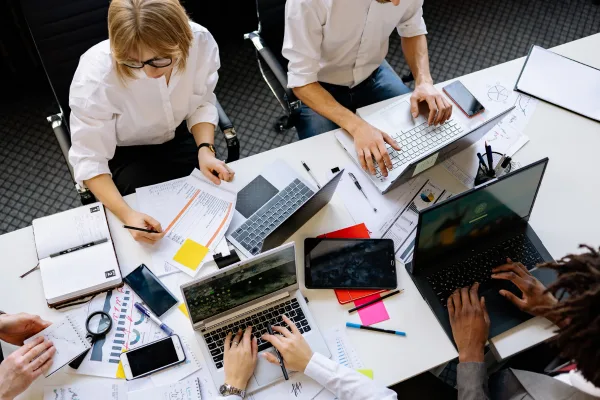 Overhead-Ansicht von Team-Mitgliedern mit Laptops und Dokumenten bei Content-Planung