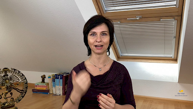 Nicole Blümlinger vor Schreibtisch sprechend, braunes Oberteil mit Muster, erklärende Geste