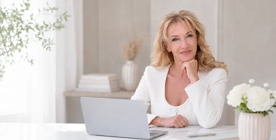 Anja Krüger sitzt am Laptop, helles Büro-Szenario mit Pflanzen und Blumen