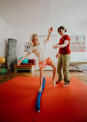 Physiotherapeutin Verena Schmalz arbeitet mit Kind auf rotem Trampolin im Therapieraum
