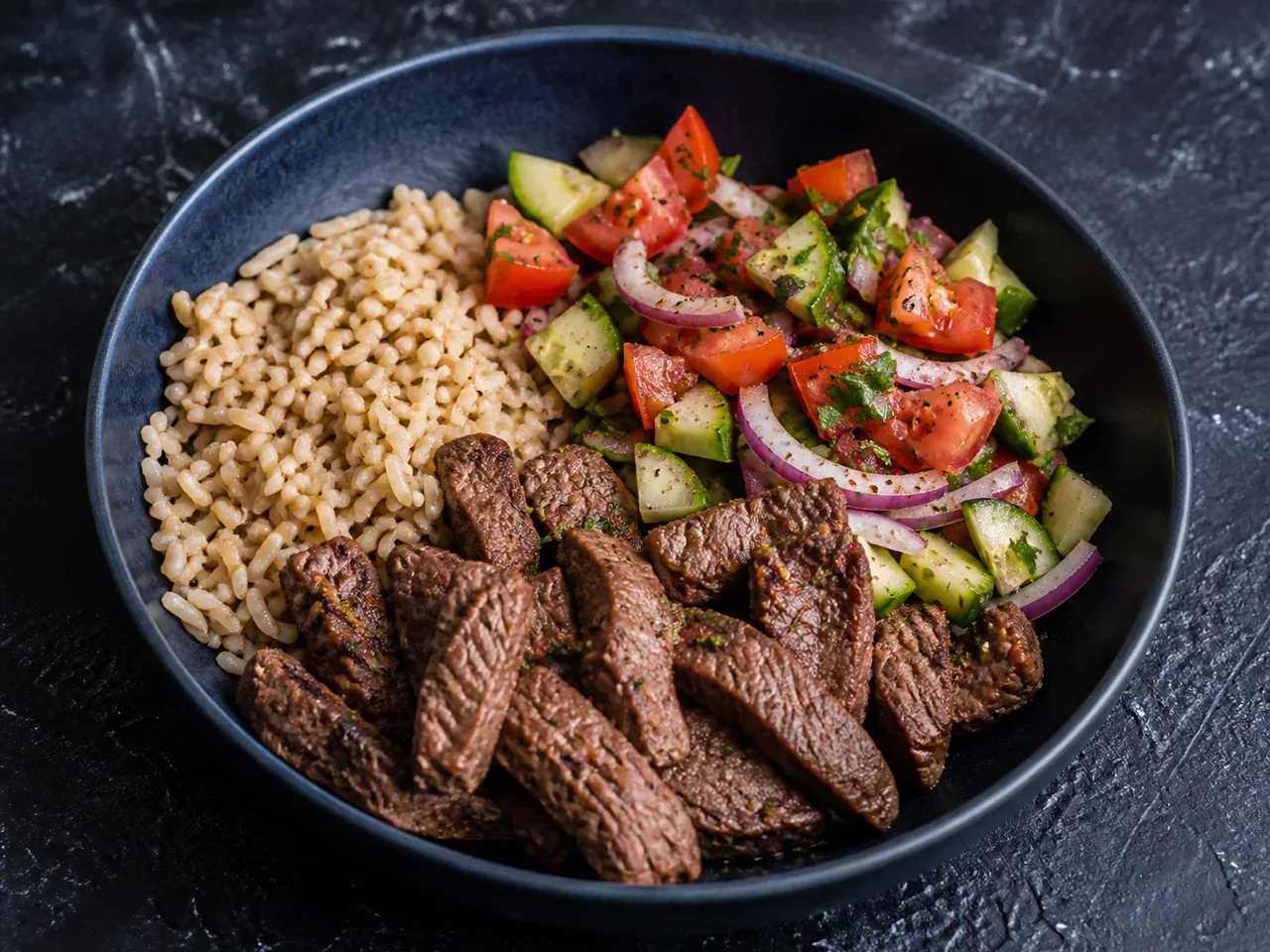 Dunkle Schale mit Rindersteak-Scheiben, Reis und gemischtem Gemüse auf dunkler Oberfläche